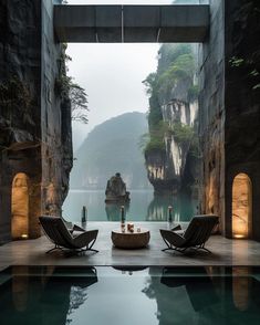 an indoor swimming pool with two lounge chairs and candles on the table next to it