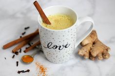 a cup of coffee with cinnamon sticks and love written on it next to some spices