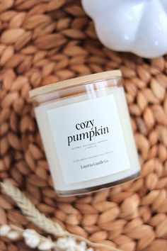 a candle sitting on top of a wicker basket next to a white ceramic pumpkin