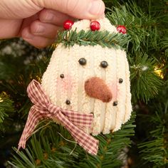 a knitted snowman ornament hanging from a christmas tree