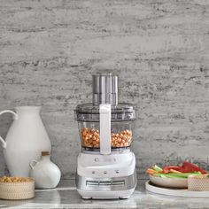 a food processor sitting on top of a counter next to plates and bowls filled with vegetables