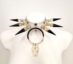 Embrace the allure of Tenebrous Divinity with our meticulously handcrafted Gothic Spike and Resin Ring Vinyl Choker.  - Each spike and resin ring is skillfully crafted by hand, adding a touch of bespoke artistry to this captivating piece.  - Made from high-quality transparent vinyl, this choker features edgy spikes and a mesmerizing resin ring, all meticulously handcrafted for a truly unique design. - The black base sets a dark and enchanting tone, complemented by transparent accents that add an intriguing touch.  - Golden glitter accents infuse the choker with a mystical radiance, while delicate gold foil details provide an exquisite finishing touch.  To enhance its mystique, the choker is accompanied by a coffin pendant, meticulously crafted with the same attention to detail. - Measuring Apocalypse Photography, Large Choker Necklace, Spiked Choker, Gothic Choker, Goth Choker, Gothic Chokers, Choker Collar Necklace, Concept Clothing, Heart Choker