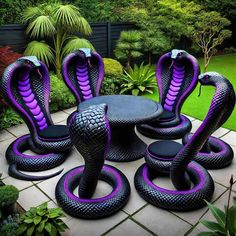 purple and black snakes sitting on top of a table in the middle of a garden