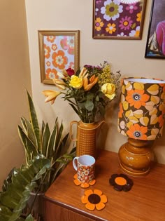 some flowers are sitting on a table next to a vase and two mugs with matching coasters