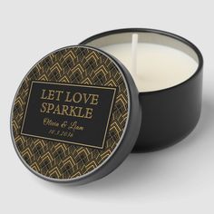 a candle that is sitting in front of a black container with the words let love sparkle on it