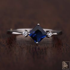 a diamond and blue sapphire engagement ring on a wooden surface with diamonds around the band