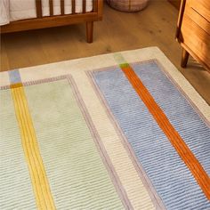 a multicolored rug on the floor in a child's room with a crib