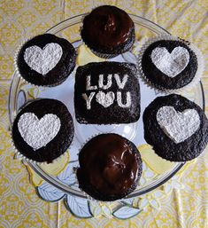 chocolate cupcakes with frosting in the shape of hearts on a glass plate