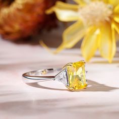 Always be on her mind when you propose with this classic three stone emerald-cut engagement ring. It is a classic piece with a lower profile that features emerald-cut yellow stone with a pair of trillion-cut white stone to bring the sparkle up. This classic designed ring will really look amazing on your bride-to-be's finger and it will be a gift that she never forgets.Carat Weight: 3.65 ctStone Size: 7*9 mmStone Type: Jeulia® StoneNumber of Stones: 1 Stone Shape: RadiantStone Color: Citrine YellowCarat Weight: 0.69 ctStone Size: 4*4 mmStone Type: Jeulia® StoneNumber of Stones: 2 Stone Shape: TrillionStone Color: Diamond WhiteWeight: 3.52 gMaterial: 925 SilverPlating Color: Silver, Yellow Gold Elegant Yellow Emerald-cut Diamond Ring, Elegant Yellow Emerald Cut Diamond Ring, Yellow Emerald Cut Diamond Ring, Gift Emerald Ring With Three Stones In Radiant Cut, Yellow Emerald-cut Promise Ring, Yellow Emerald Cut Promise Ring, Emerald Engagement Ring Cut, Yellow Stone, Stone Engagement Rings