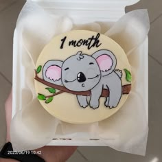 a cake in the shape of a koala on a tree branch with one month written on it