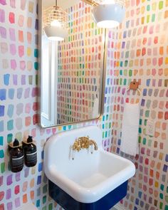 a white sink sitting under a bathroom mirror next to a wall mounted faucet