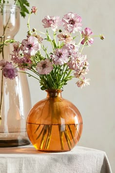 two vases with flowers in them sitting on a table next to each other,