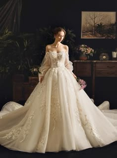 a woman in a white wedding dress standing on a bed with her arms behind her back