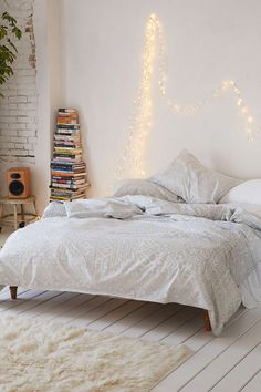 a bedroom with a bed, bookshelf and lights on the wall above it