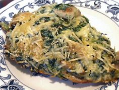 a white and blue plate topped with meat covered in grated cheese on top of spinach