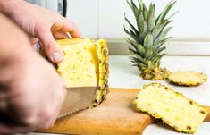 someone slicing up a pineapple on a cutting board next to some sliced pineapples