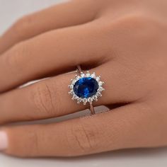 a woman's hand with a blue and white diamond ring on her left hand