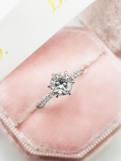 an engagement ring sits in a pink velvet box