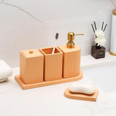 an orange bathroom set with soap, toothbrush holder and sponge dispenser