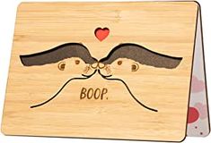 a wooden plaque with two faces and the words boop on it