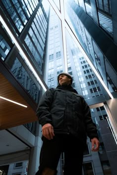 a man standing in front of a tall building with lots of windows on the side