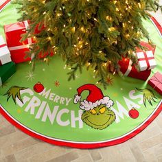 a christmas tree with presents under it and a merry grino sign on the floor