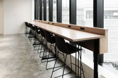 a row of bar stools sitting next to a window in a room with lots of windows