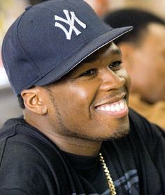 a man wearing a new york yankees hat smiles at the camera while sitting in front of other men