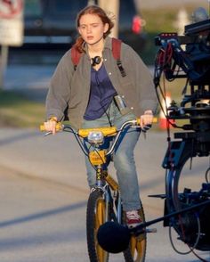 a woman riding a bike with a camera attached to the handlebars and seat