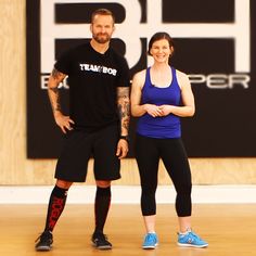 a man and woman standing in front of a wall with the word fit written on it