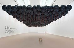 an art installation in a white room with black balloons hanging from it's ceiling