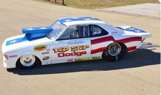 an old race car with the american flag painted on it's side sitting in a parking lot