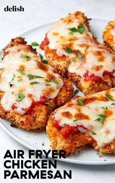 four chicken parmesan patties on a white plate with sauce and green garnish