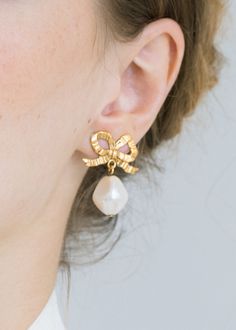 The Khloe Earrings will be the chameleon of your jewelry wardrobe, with a neutral palette loaning versatility to elevate any look. The golden ribbon of these bow earrings has a sculptural nature that suggests movement, and we love the gentle swaying of the baroque crystal pearl drops. We also suggest the larger Eloise Earrings for a statement look. Luxury High Luster Pearl Earrings As Gift, Luxury Pearl Earrings As A Gift, Luxury Designer Pearl Earrings For Gift, Luxury Feminine Pearl Earrings, Luxury Hand Set Pearl Earrings For Gifts, Luxury Plated Pearl Earrings As Gift, Luxury Dainty Pearl Earrings As Gift, Macy's Luxury Classic Earrings, Luxury Timeless Design Earrings As Gift