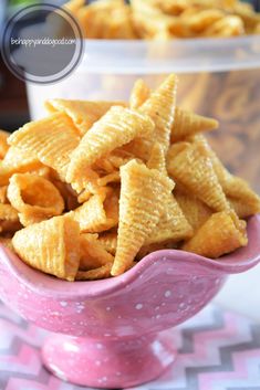 a pink bowl filled with cheetos sitting on top of a checkered table cloth