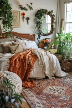 a bed with lots of pillows and blankets on top of it next to potted plants