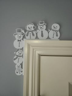 some white paper cut out of snowmen on top of a door handle and frame