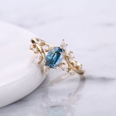 a gold ring with an oval blue topazte surrounded by small white and yellow diamonds