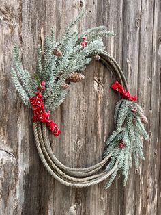 Christmas wreath made from a team roping lasso, used in actual rodeo competition!  Wreath is adorned with snowy rustic garland, pinecones, specs of holly, and finished with red western paisley ties.  Perfect for your front door, on the outside of your barn, or just as wall decor! Rope Wreath Diy Western, Christmas Rope Wreath, Ranch Christmas Decor, Lasso Wreath, Boot Wreath, Western Christmas Decorations, Western Wreath, Rope Wreath Diy, Rope Wreaths