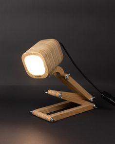 a wooden desk lamp with a white light on it's base and black background