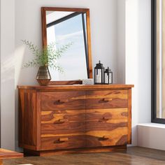 a wooden dresser sitting next to a window with a large mirror on top of it