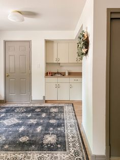 a large rug in the middle of a room with white cabinets and cupboards behind it