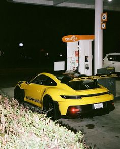 a yellow sports car parked at a gas station