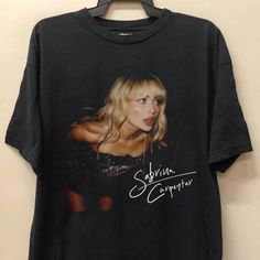 a black t - shirt with an image of a blond haired woman on it's chest