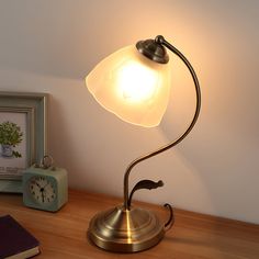 a lamp that is sitting on top of a table next to a clock and some books