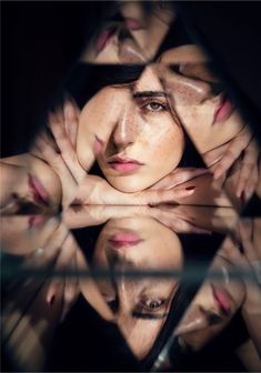 a woman with her hands on her face looking at the camera through a glass window