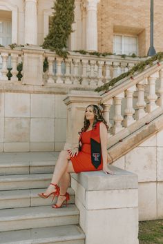 a woman is sitting on the steps in an orange dress and red heels with her legs crossed