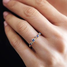 a woman's hand with a blue and white diamond ring on her left hand