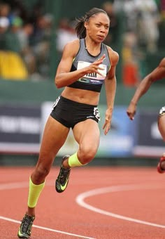 a woman running on a track with other people watching