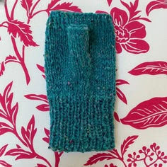 a pair of blue knitted mittens sitting on top of a floral print tablecloth